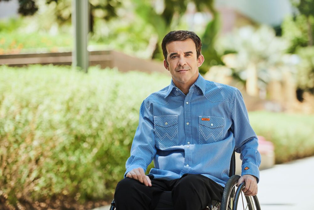 Natural dating profile photo for men in San Francisco, Outdoor portrait of a man using a wheelchair in a blue button down shirt, Approachable dating app photo for Hinge Bumble and Tinder, Online dating photographer San Francisco image with relaxed lifestyle setting.