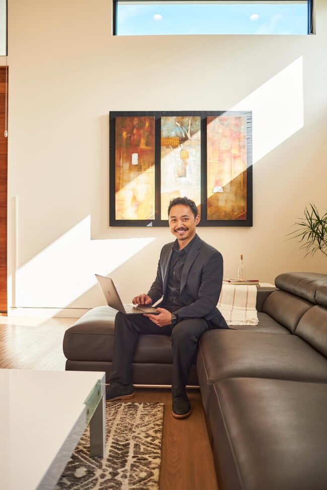 Realtor lifestyle photo in Los Angeles, professional man seated with a laptop in a modern living room, polished image for realtor website, Zillow profile, social media, marketing, and personal branding