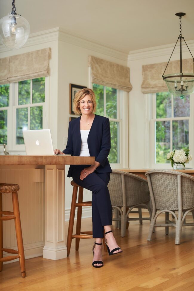 Realtor lifestyle photo in Los Angeles, professional woman seated with a laptop in a bright home dining area, polished image for realtor website, Zillow profile, social media, marketing, and personal branding