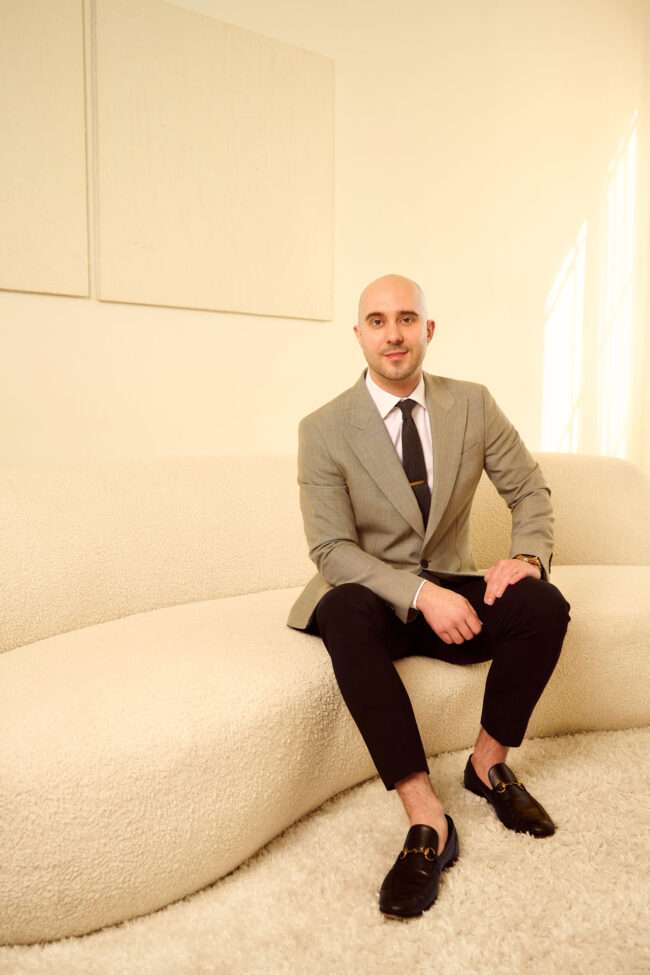 Professional headshot in Los Angeles, polished environmental portrait of a man in a suit seated in a modern interior, useful for website bio, LinkedIn profile, speaker page, press feature, and professional use