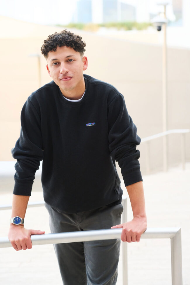 Man wearing a black sweatshirt in a relaxed outdoor dating profile photo.
