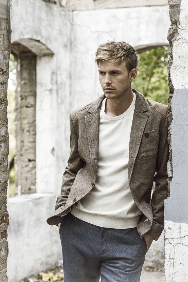 Man wearing a textured blazer and light sweater in a neutral outfit for dating profile photos.