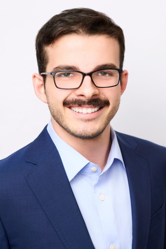 Professional business headshot in Los Angeles, clean studio portrait with blue suit and glasses, LinkedIn and company website profile image