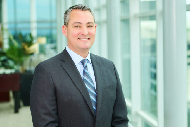 Professional headshot in Los Angeles, man in a gray suit photographed in a bright office setting, useful for website bio, LinkedIn profile, resume, company profile, and professional use