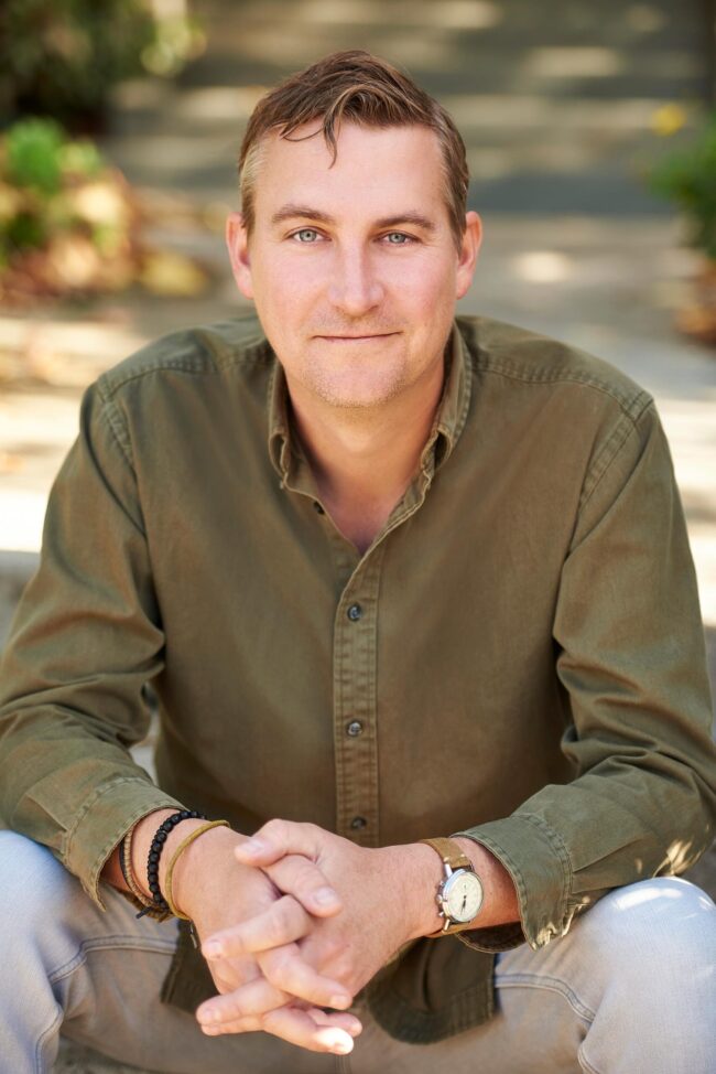 Outdoor professional headshot in Los Angeles, man photographed in a relaxed natural setting with an approachable expression, useful for website bio, LinkedIn profile, professional profile, personal website, and online presence