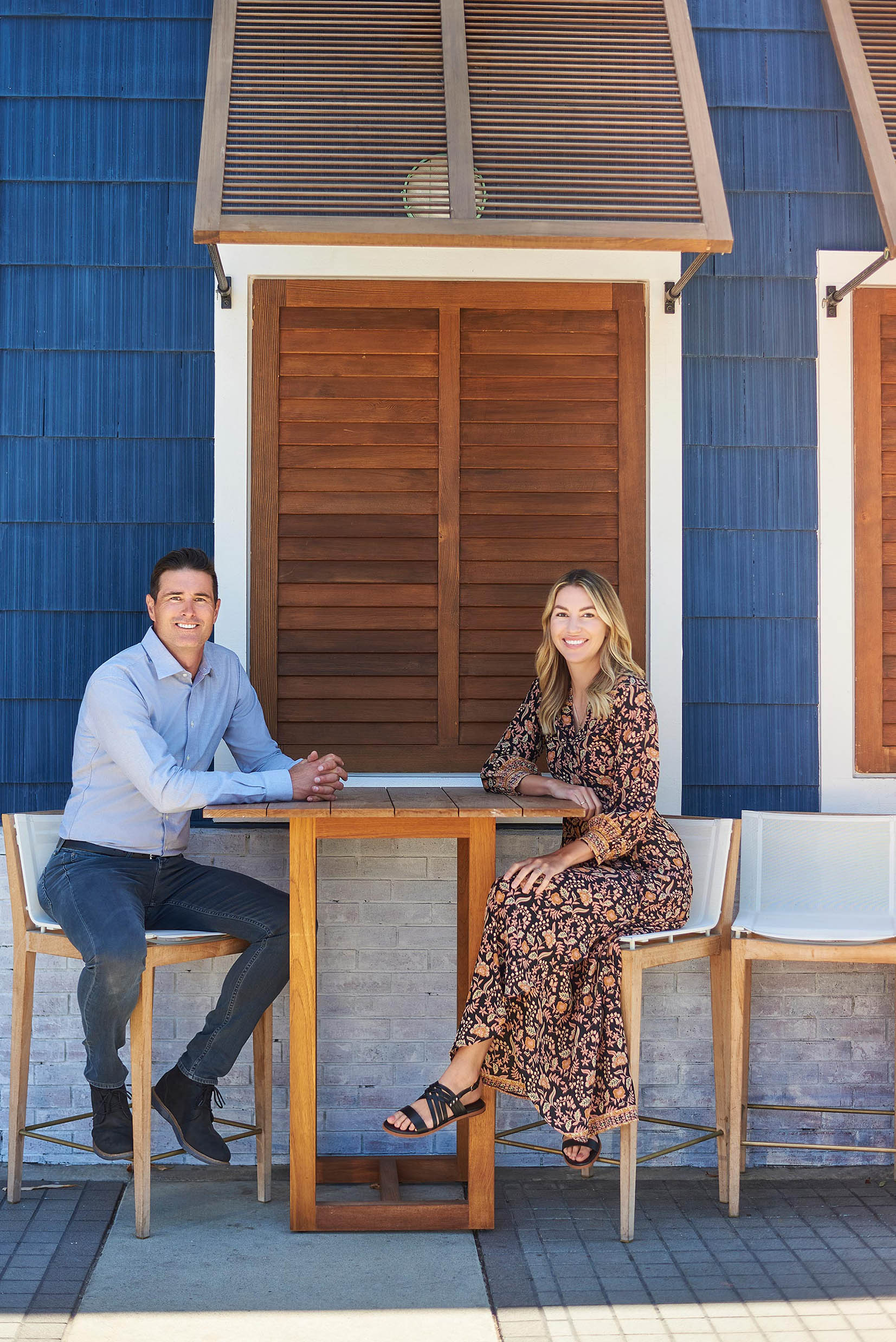 Outdoor Cafe Conversation for First Date Timing Man and woman seated at a small outdoor table in front of blue siding and wood shutters.