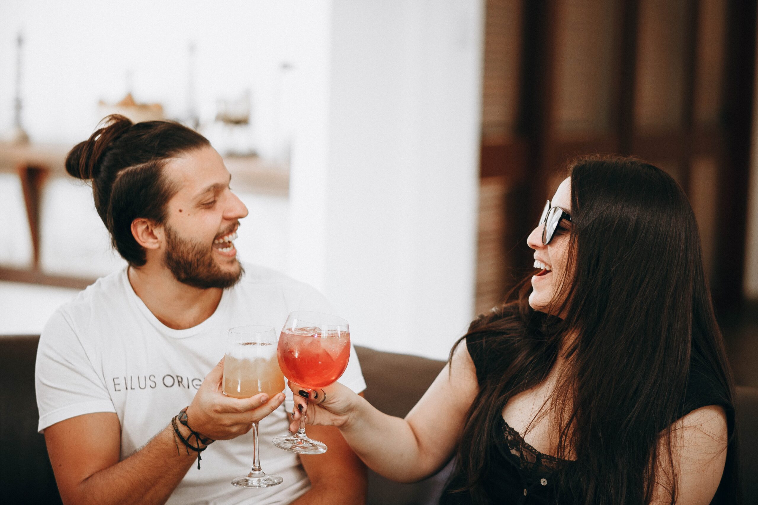 Drinks and Conversation for First Date Length Man and woman laughing together while holding drinks during a casual first date.